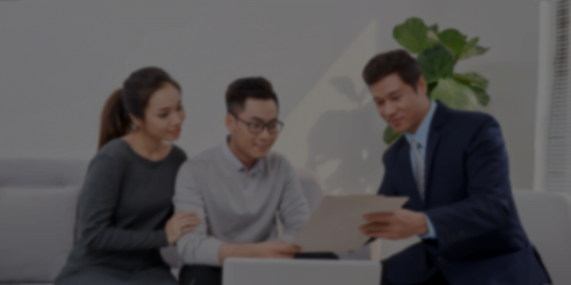 Businessman talking to couple on the couch with laptop and documents on table