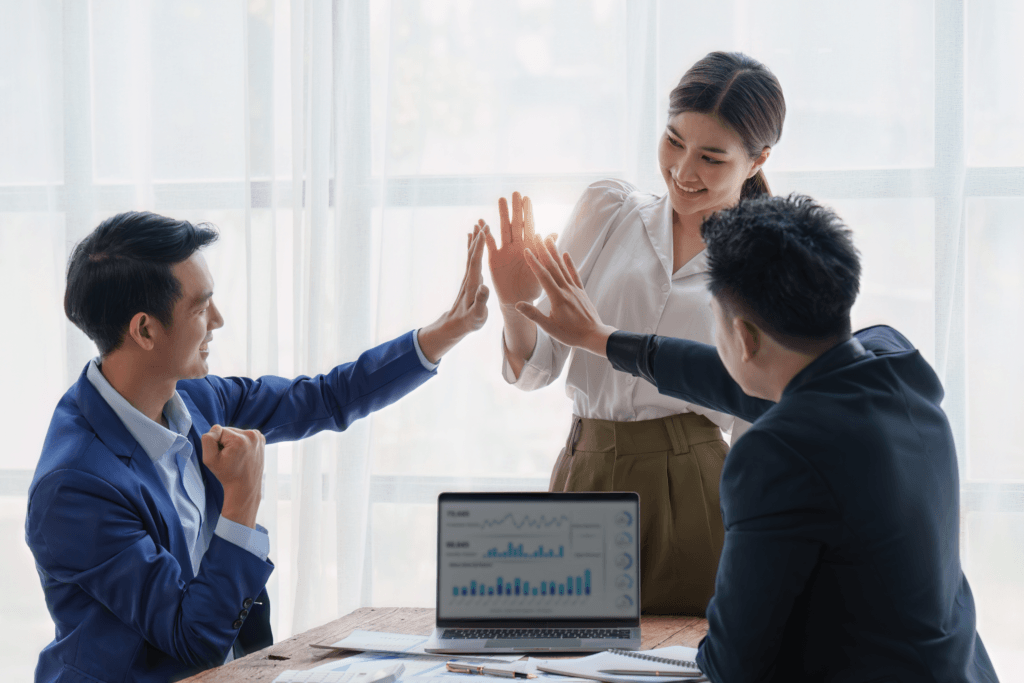 business-team-high-fiving-at-meeitng-table